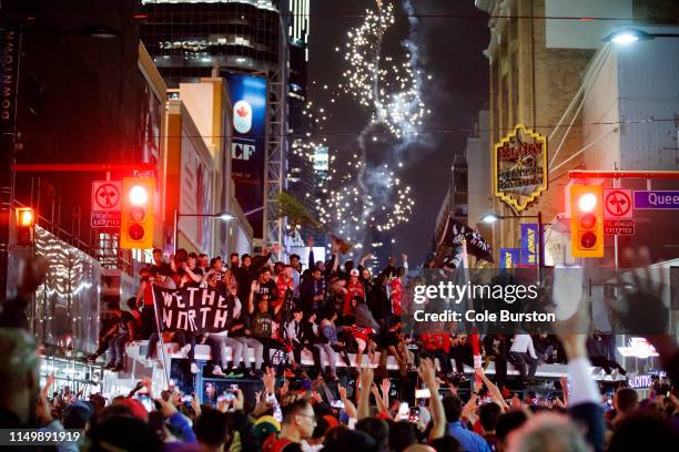 Toronto Raptors fans celebrate atop a bus after the team beat the Golden State Warriors in Game Six of the NBA Finals, on June 13, 2019 in Toronto,...