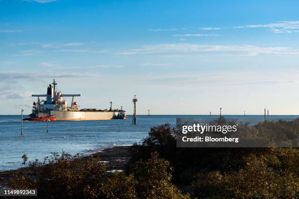 Tugs guide a bulk carrier loaded with iron ore out to sea from the port in Port Hedland, Australia, on Monday, March 18, 2019. The two parts of the...