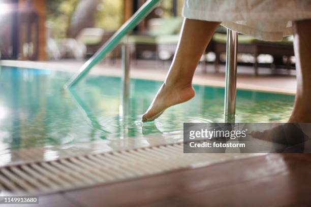 vrouw in badjas dompelen tenen in zwembad - spa stockfoto's en -beelden