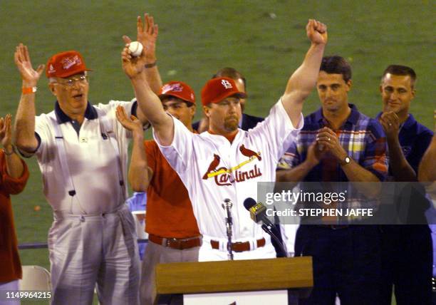 Mark McGwire of the St. Louis Cardinals holds the ball he hit for his 62nd home run of the season against the Chicago Cubs, which was given to him by...