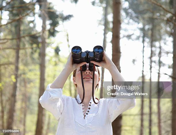 woman looking through binoculars in forest. - bird watching stock pictures, royalty-free photos & images