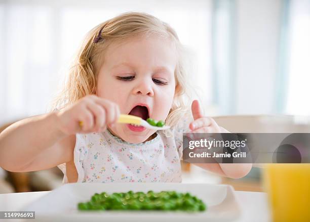 toddler eating peas with spoon - kids eating stock pictures, royalty-free photos & images