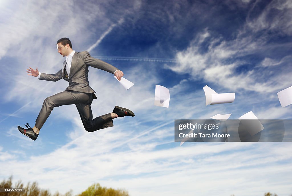 Business man in mid air with paper