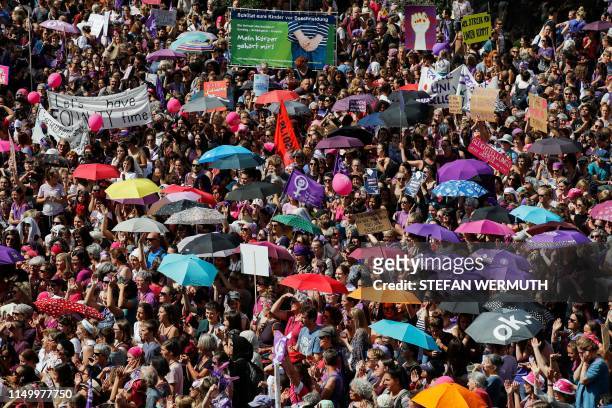 Women hold signs and umbrellas as they take part in a nation-wide women's strike for wage parity outside the federal palace, on June 14, 2019 in the...