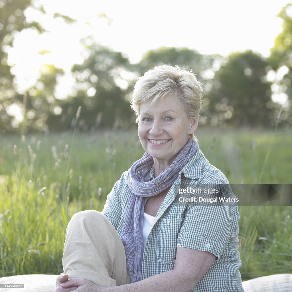 Senior woman sitting in meadow.