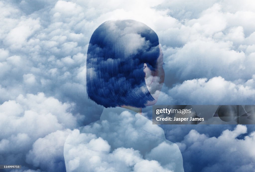 Double exposure of woman looking in to clouds
