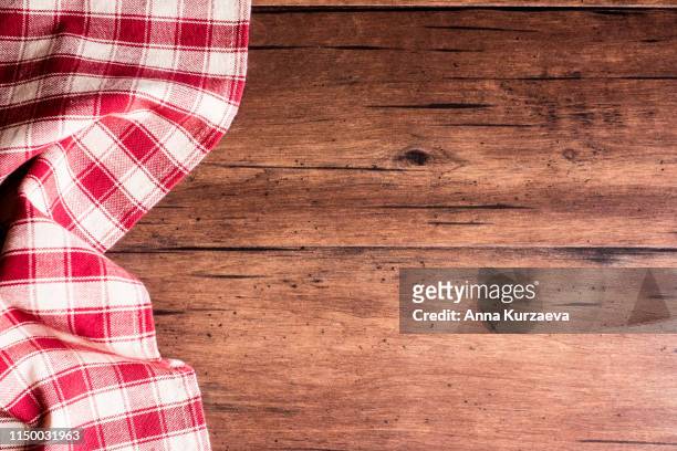 checkered red napkin on an old wooden brown background, top view. image with copy space. kitchen table with a towel - top view with copy space. - rood kleed stockfoto's en -beelden