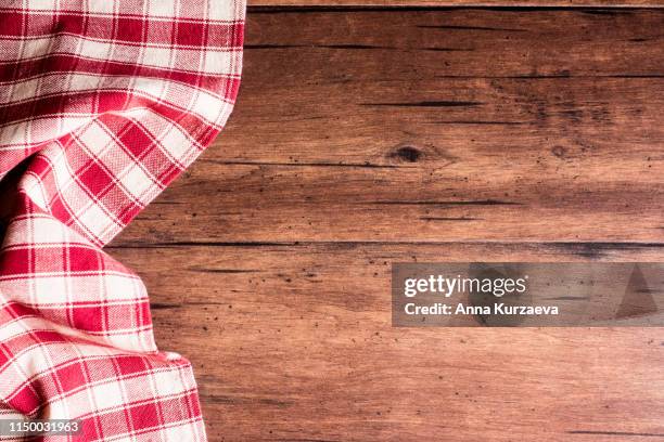 checkered red napkin on an old wooden brown background, top view. image with copy space. kitchen table with a towel - top view with copy space. - gingham stock pictures, royalty-free photos & images