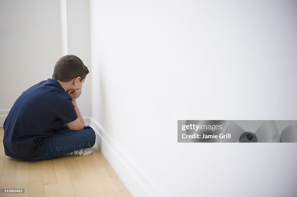 Young boy sulking in corner
