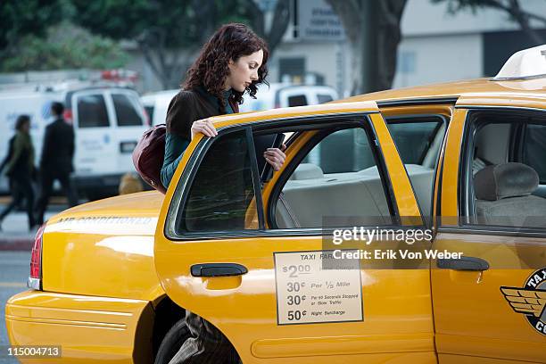 woman holding a laptop getting in a taxi - taxi imagens e fotografias de stock