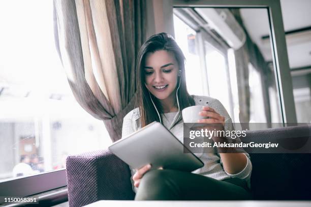 female enjoying coffee and watching movie on digital tablet - get out film 2017 stock pictures, royalty-free photos & images