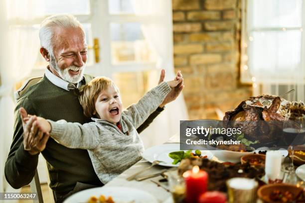 grand-père et petit-fils heureux s’amuser pendant le déjeuner de thanksgiving à la maison. - thanks giving meal photos et images de collection