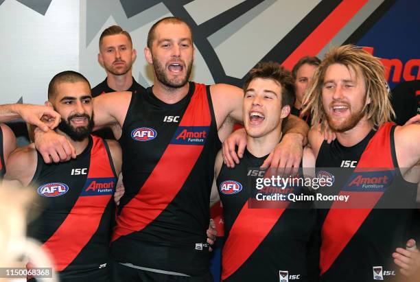 Adam Saad, Tom Bellchambers, Zach Merrett and Dyson Heppell of the Bombers sing the song in the rooms after winning the round nine AFL match between...
