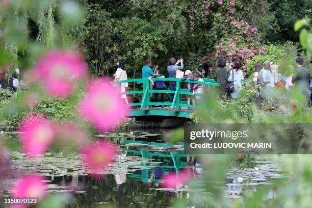 People take pictures from the bridge at the nympheas pond garden as they visit the Claude Monet house and foundation, on june 14 in Giverny.