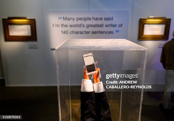 Display of a phone with tiny hands is seen near tweets by US President Donald Trump at "The Daily Show Presents: The Donald J. Trump Presidential...