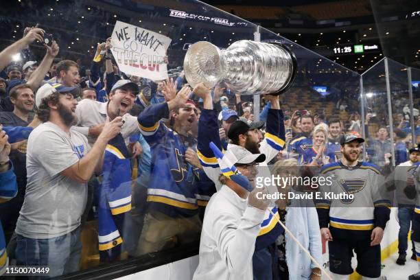 St. Louis Blues Robert Bortuzzo victorious holding Stanley Cup over his head on ice with his father Oscar and mother after winning game vs Boston...
