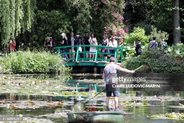 Gardner on a boat cleans the nympheas' pond while people visit the gardens of Claude Monet house and foundation, on june 14 in Giverny.