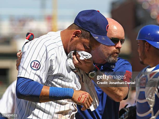 Trainer Ed Halbur of the Chicago Cubs helps Aramis Ramirez off of the field after Ramirez was hit in the mouth by the ball against the Houston Astros...