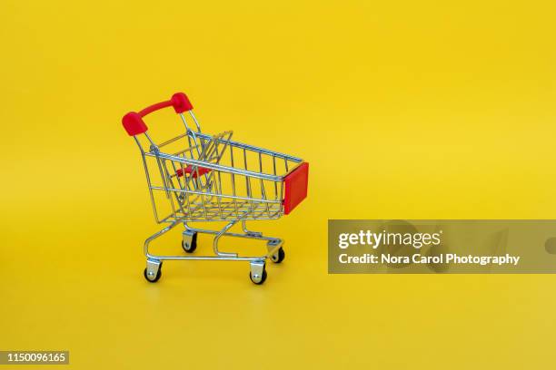 shopping trolley on yellow backgrounds - shopping trolleys stockfoto's en -beelden