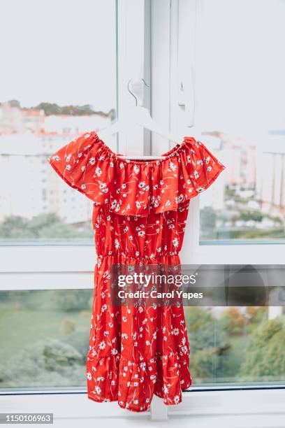 red floral dress hanging in hanger - red dress stock pictures, royalty-free photos & images