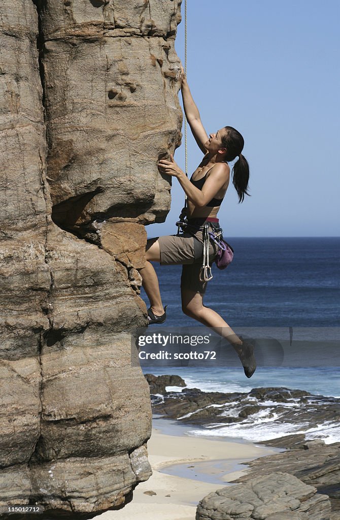 Side-view of a woman climbing a rocky cliff