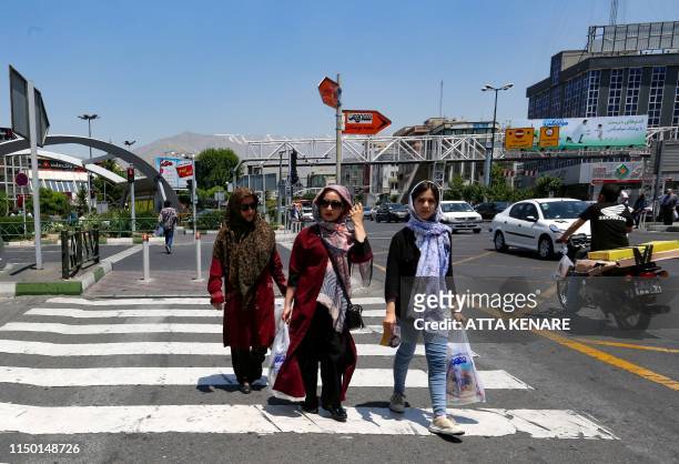 Iranian women carry their shopping bags as they cross a road in the Iranian capital Tehran on June 15, 2019. - US President Donald Trump last year...