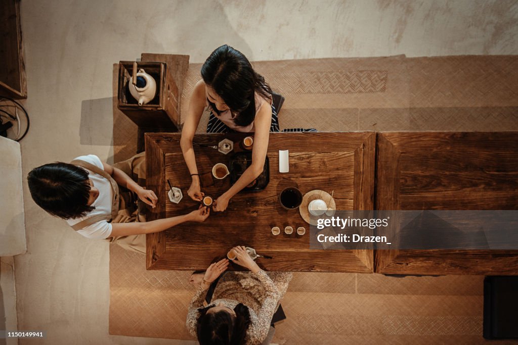 High angle view of three millennial women in Asia, drinking tea and eating cake.