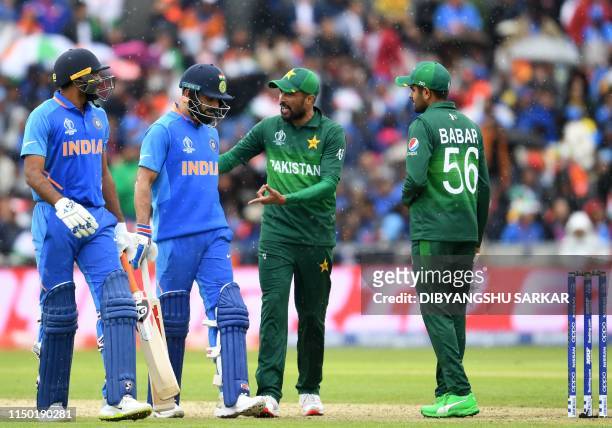 Pakistan's Mohammad Amir and teammate Babar Azam speak with India's captain Virat Kohli and India's Vijay Shankar as they walk back to the pavilion...