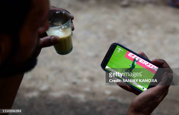An Indian fan watches a live broadcast of the Cricket World Cup match between India and Pakistan on a mobile phone in Allahabad on June 16, 2019.