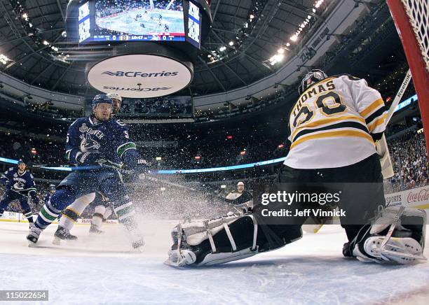 Christian Ehrhoff of the Vancouver Canucks watches Tim Thomas of the Boston Bruins make a save in Game One of the 2011 NHL Stanley Cup Finals at...