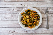 olorful bowl of uncooked tomato and spinach fusilli pasta, a traditional Italian pasta made from spirals and corkscrews of dried durum wheat dough, on a rustic wooden background with copy space