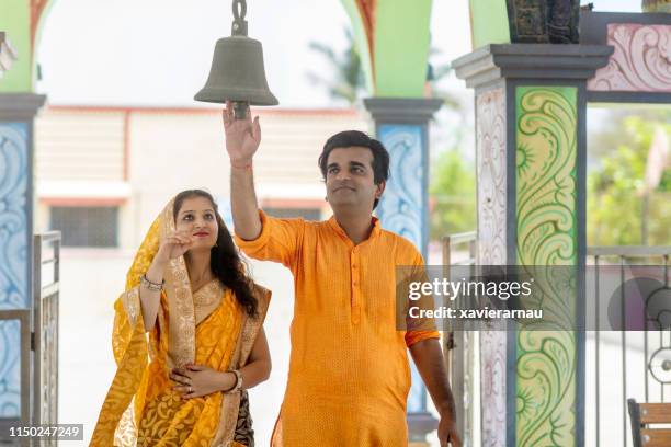 couple ringing bell before entering hindu temple - bell stock pictures, royalty-free photos & images