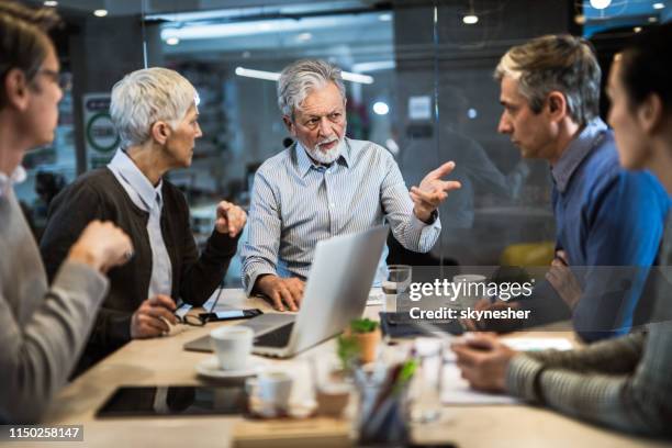 senior ceo talking to his colleagues on a meeting in the office. - working seniors stock pictures, royalty-free photos & images