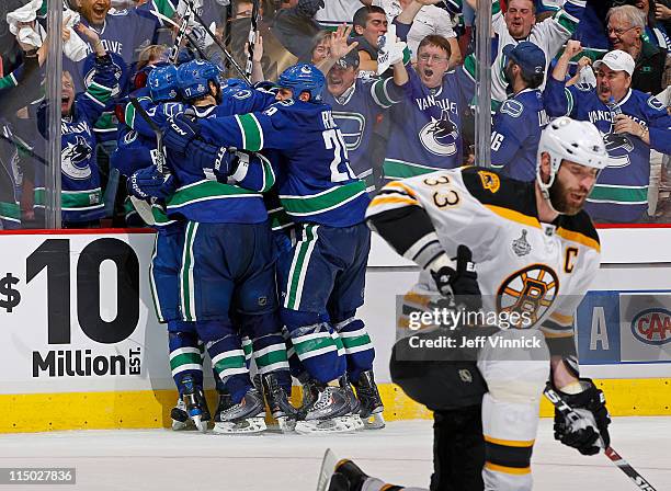 Raffi Torres of the Vancouver Canucks celebrates his game winning third period goal with teammates, while Zdeno Chara of the Boston Bruins looks on...