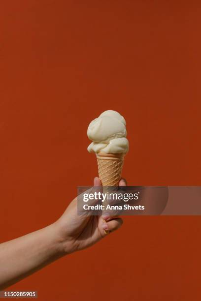 ice cream cones against a terracotta wall - hand holding ice cream cone stock pictures, royalty-free photos & images