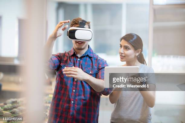 colleagues using a vr headset - casques réalité virtuelle photos et images de collection
