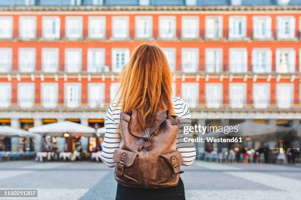 spain, madrid, plaza mayor, back view of redheaded young woman with backpack in the city - madrid foto e immagini stock