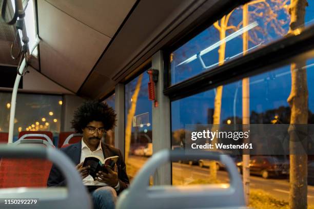 spain, barcelona, businessman in a tram at night reading a book - city book stock pictures, royalty-free photos & images