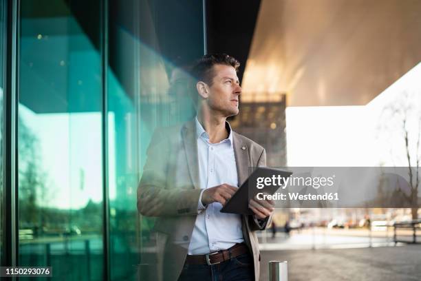 businessman using tablet outside a building in the city - light reflection stock-fotos und bilder