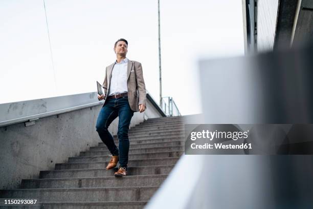 businessman walking down stairs - business person ipad travel stock-fotos und bilder