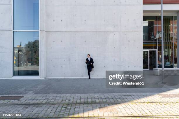 italy, florence, young businessman leaning against a building in the city - façade immeuble photos et images de collection