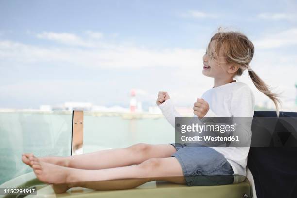 happy little girl sitting on lounger clenching fists - little ballet stock-fotos und bilder