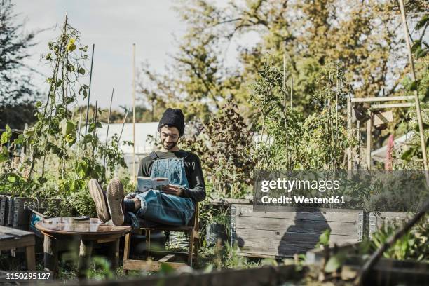 smiling man reading book in urban garden - le cap - fotografias e filmes do acervo