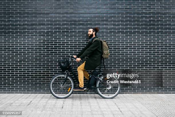 man riding e-bike along a brick wall - wall e stock pictures, royalty-free photos & images