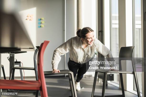 happy businesswoman exercising in office - athleticism stockfoto's en -beelden