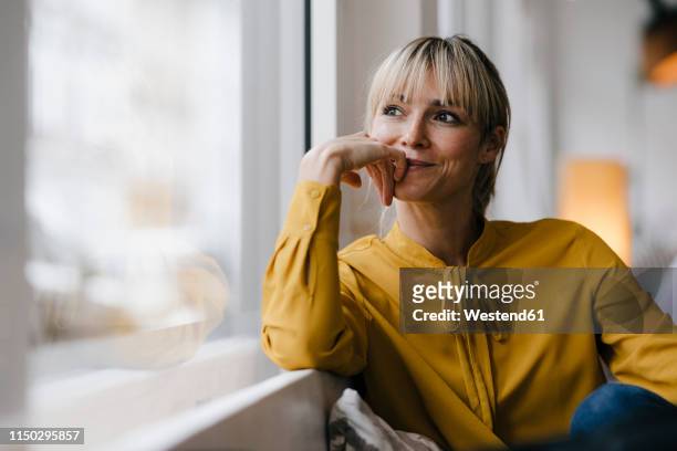 portrait of a beautiful blond woman, looking out of window - yellow stock-fotos und bilder