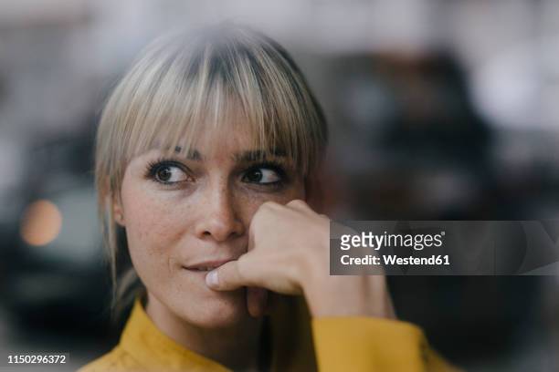 blond businesswoman sitting at window, thinking - entscheidung stock-fotos und bilder
