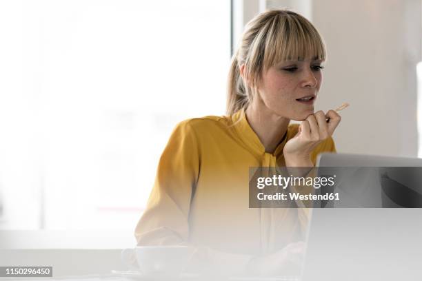 blond woman doing online payment with her credit card - red blouse fotografías e imágenes de stock