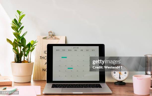 opened laptop with a calendar on desk at home office - abandoned home stock-fotos und bilder