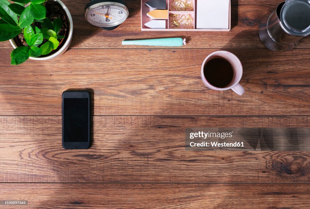 Wooden office desk with smartphone and coffee mug, top view